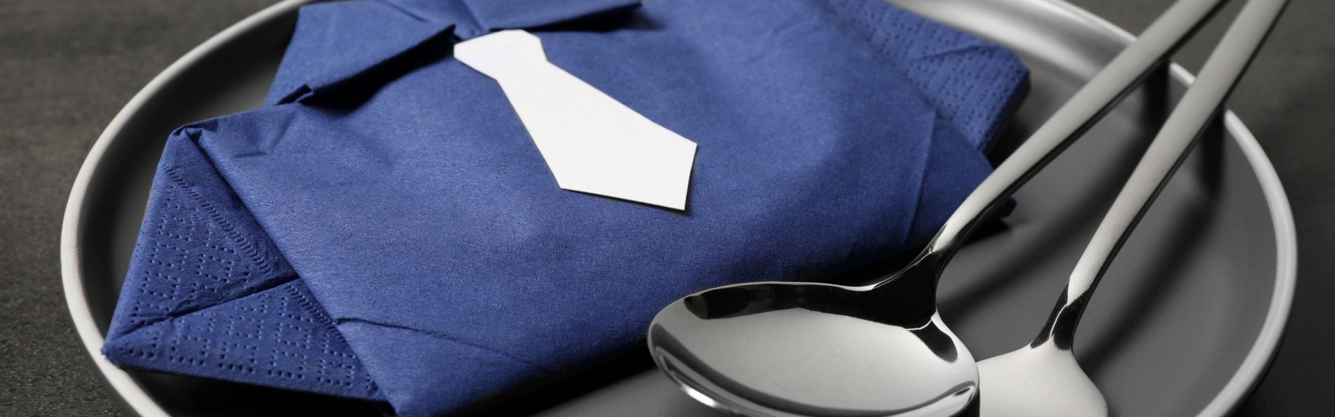 Eine zu einer Krawatte gefaltete Serviette auf einem Teller